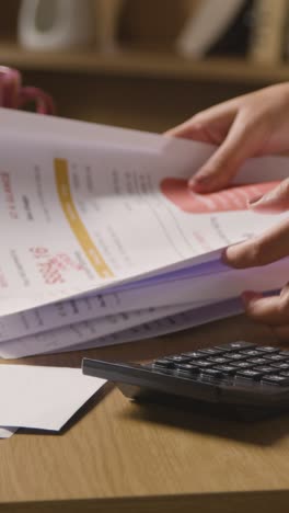 Vertical-Video-Of-Woman-Using-Calculator-To-Check-Household-Bills-And-Domestic-Finances-In-Cost-Of-Living-Crisis